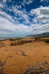 View of sand dunes on the Guincho beach near Atlantic coast. Landscape of sunny day, blue sky and a mountain in background. Cascais. Portugal.