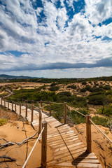 Fototapeta na wymiar View of sand dunes on the Guincho beach near Atlantic coast. Landscape of sunny day, blue sky and a mountain in background. Cascais. Portugal.
