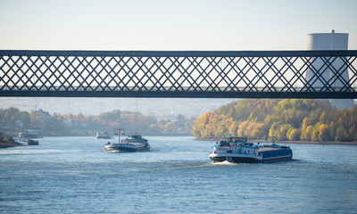 Sunny autumn day in Germany on the river Rhine. The barge flows under the railway bridge. A visible...