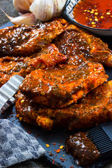 Steakfleisch für den Grill würzen mit Chillsauce auf dunklem Untergrund