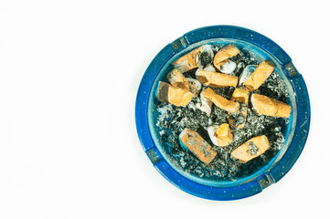 Dirty blue glass ashtray full of cigarette buts and ash after smoke, partially isolated on white background view from above