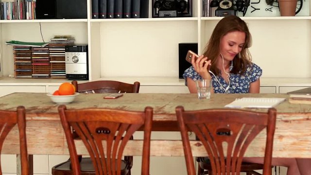 Young woman listen to music sitting by table at home
