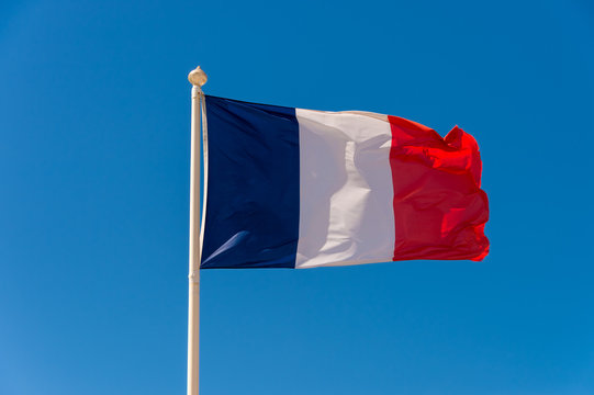 French flag waving against blue sky in Wimereux, France.