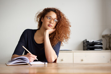 female student sitting at desk and writing notes in book