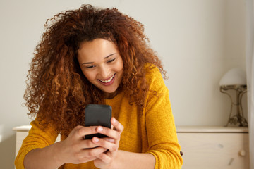 Close up happy young mixed race woman smiling and looking at mobile phone