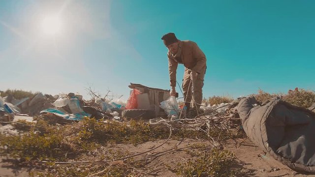 dirty homeless man at the dump slow lifestyle motion video. homeless roofless person looking for food in a dump. refugee homeless illegal immigration poverty concept