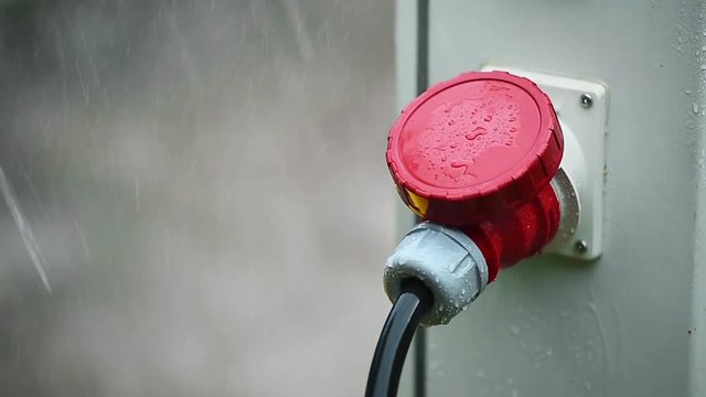 Raindrops are seen on industrial electric plug during heavy rain