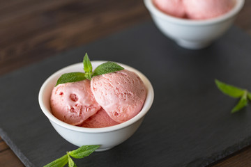 Strawberry Ice Cream balls  In Bowl with mint over black background.