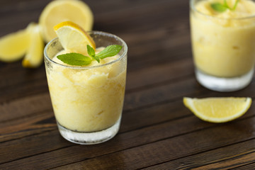Fresh lemon citrus sorbet garnished with mint alongside.  Lemon Frozen Granita Slush Drink. 