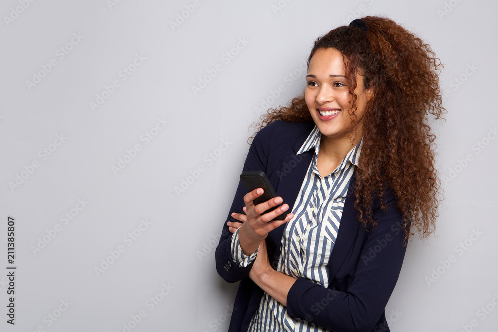 Wall mural attractive young businesswoman with curly hair smiling with mobile phone