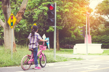 girl is cycling in the park, bicycle stops at traffic lights
