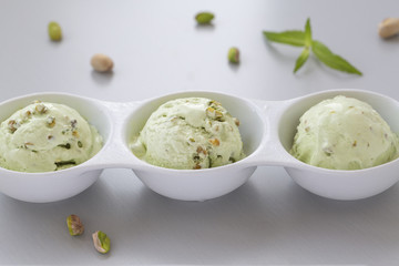 Pistachio ice cream in white bowl. Fresh pistachio ice cream, nuts and mint.