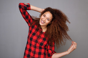 Fototapeta premium cheerful young woman smiling with hand in curly hair