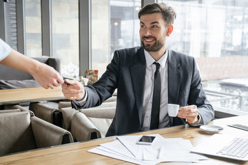 Businessperson on business lunch at restaurant sitting paying to waitress for coffee smiling