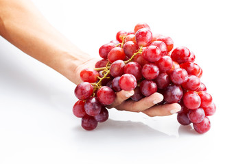 Hand holding fresh red bunch of grapes isolated on white background.