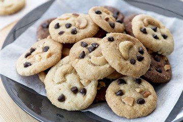 groups of Delicious Chocolate Chip Cookies on black plate, Tasty Homemade cookies on wooden table, close up dessert