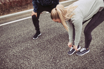 Young woman tying her running shoes before a jog