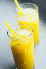 Glasses of orange juice with ice on a white background.