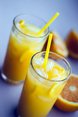 Glasses of fresh orange juice with ice and orange slices on a white background.
