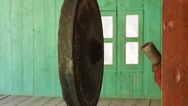 Young monk beats in big gong in nepalese village Lho, Nepal.