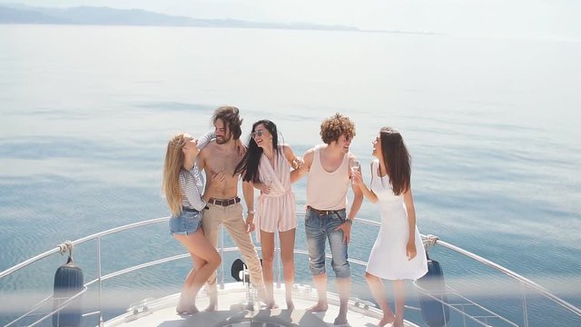 Marine cruise and vacation - youngsters with champagne glasses on boat or yacht