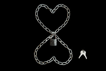 Fototapeta na wymiar Two chained hearts locked with a padlock with keys on black background. Wedlock concept, lined with chain