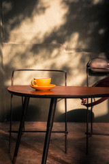 Specialty filter coffee in yellow cup on a wooden table at the hipster coffee shop. Sunlight. Vintage color filter effect. Copyspace; vertical