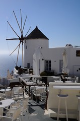 Famous stunning view of white architectures and windmill above the volcanic caldera in the village of Oia in Santorini island, Greece