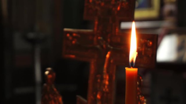 The flame of a candle on the background of the crucifixion of Jesus Christ. Video close-up.
