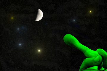 universe - green alien hand with outstretched finger pointing to the moon and the stars