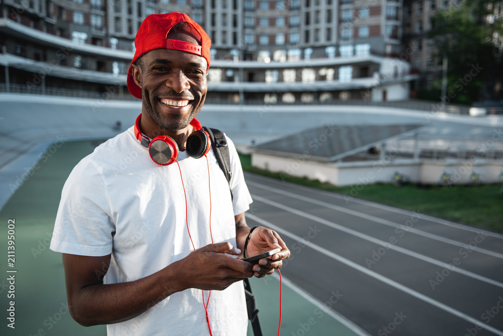Poster portrait of cheerful man with attractive smile using modern phone before making exercise. copy space