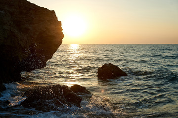 Splash waves hit rocks with the beautiful sunset and sky.