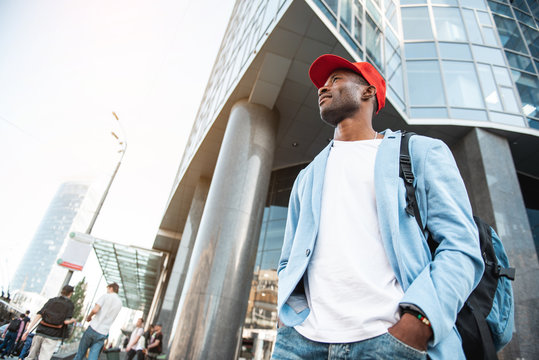 Low Angle Side View Beaming Male Traveler Going At Street Near Building. Copy Space