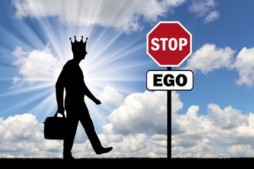 Silhouette of a selfish man with a crown on his head and a road sign of a stop ego
