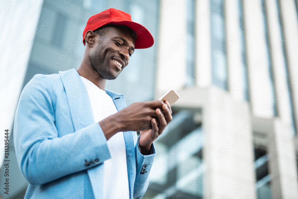 Poster low angle portrait of glad man sending message by while going in town. copy space