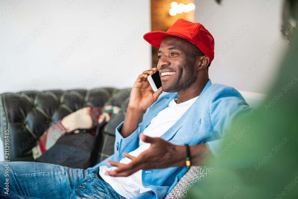 Aufkleber portrait of satisfied man telling by phone while resting on sofa. he gesticulating hands