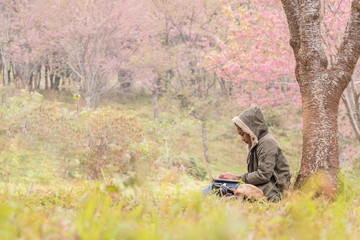 Asian girl using a laptop under the tree