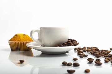 Tazza di caffè bianca con chicchi con un leggero riflesso