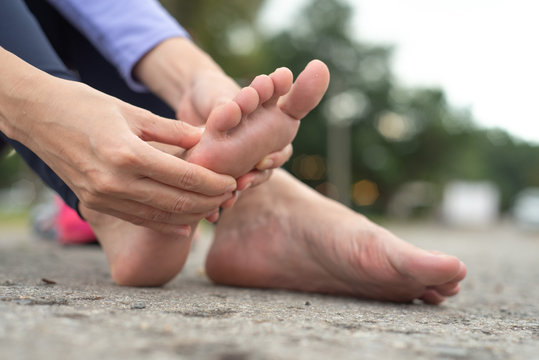 woman feeling pain in her foot during sport outdoor