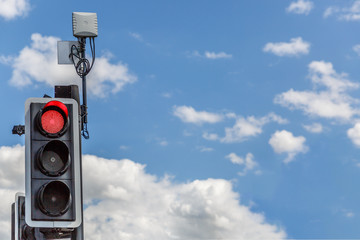 Traffic light illuminated in red, with a lovely sky background