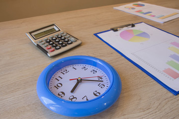 Clock, calculator, pen, graphics on table. Businesses concept