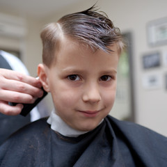 Barber making a haircut to a boy with clipper.
