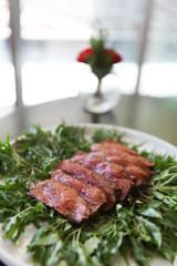 Grilled and seasoned medium rare cook beef on a bed of contrast green leaves at a Starred restaurant in Bangkok. Selective Focus.