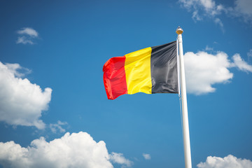 flag of Belgium in the sky/ Belgium flag in the wind on a flagpole against a background of clouds in the sky