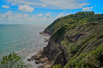 the mountain hill have many green trees in the sea with cloudy blue sky.