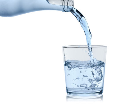 water from the sweating bottle is poured in a glass glass, isolated on a white background