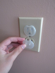 A person inserting a baby proof safety outlet cover into an American outlet