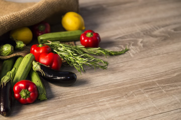 organic vegetables and wicker bag on the wooden background.Eggplant ,pepper,zucchini on the ground.