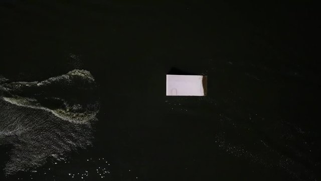 Aerial shot of a cableway in a lake with a wakeboarder grinding and rotating on a funbox
