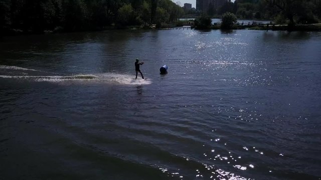 Aerial shot of a cableway in a lake with a wakeboarder grinding and rotating on a funbox